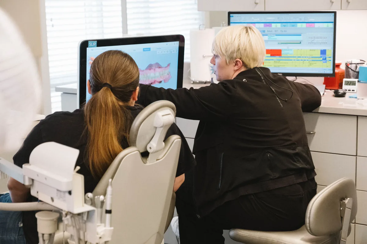 Staff member pointing out details on a digital teeth scan to a seated patient in the treatment chair at Schoettger Orthodontics.