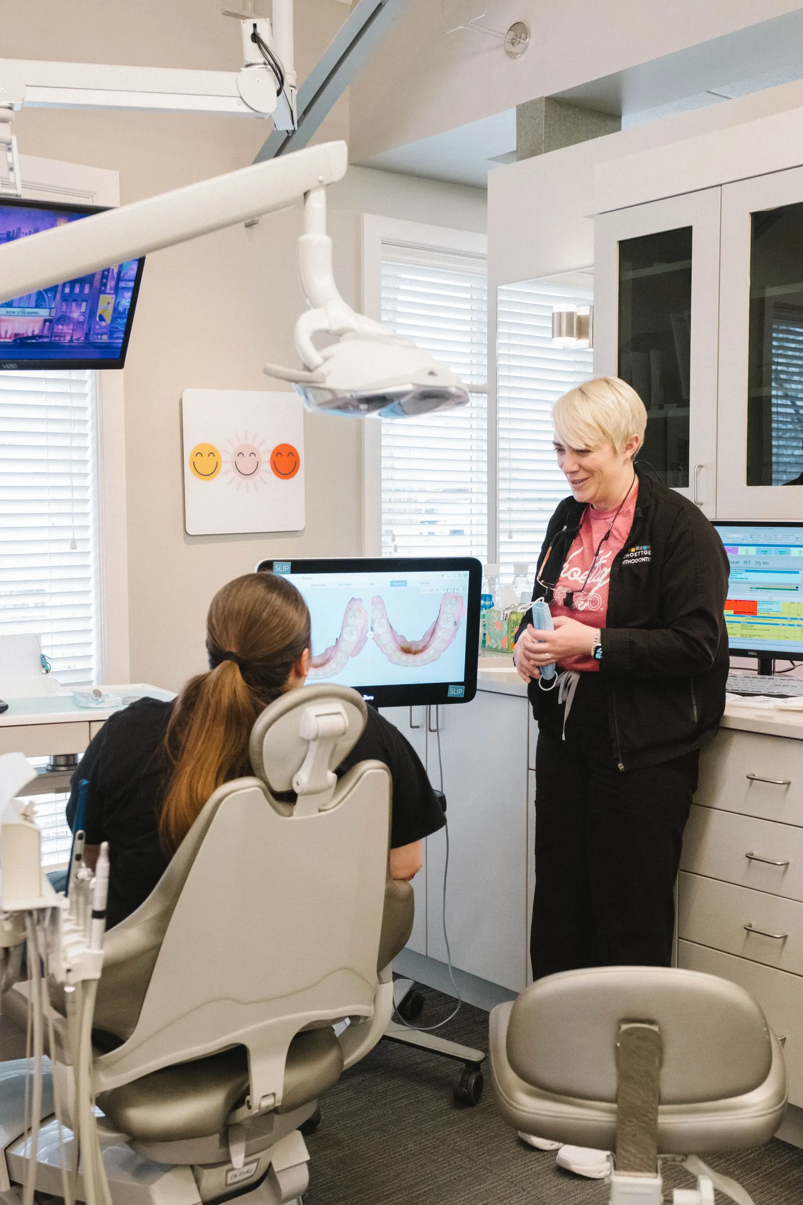 Dentist discussing dental impressions on a screen with a patient seated in a dental chair.