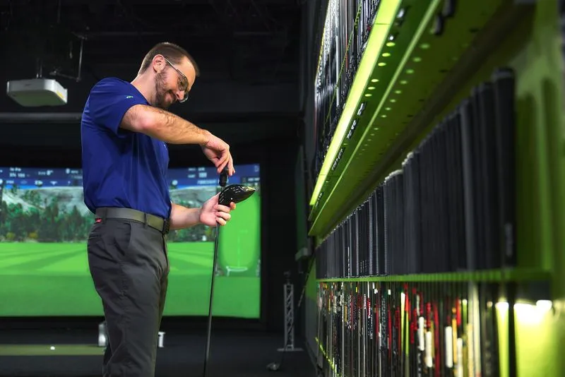 GOLFTEC coach tightening club head to shaft during indoor custom club fitting.