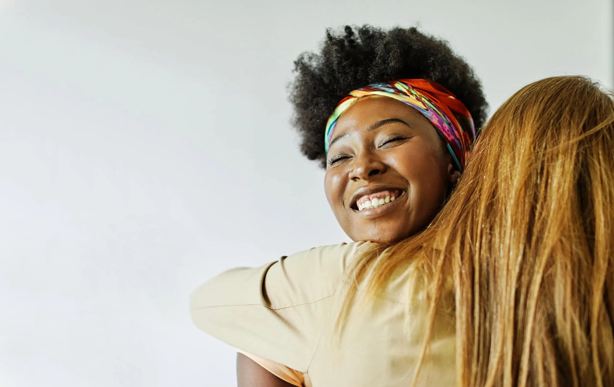 A woman is hugging another woman with a smile on her face.