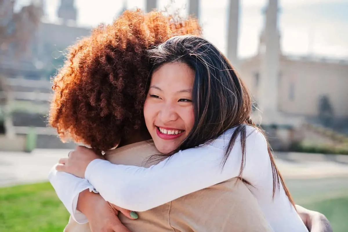 A woman hugging another woman in a park.