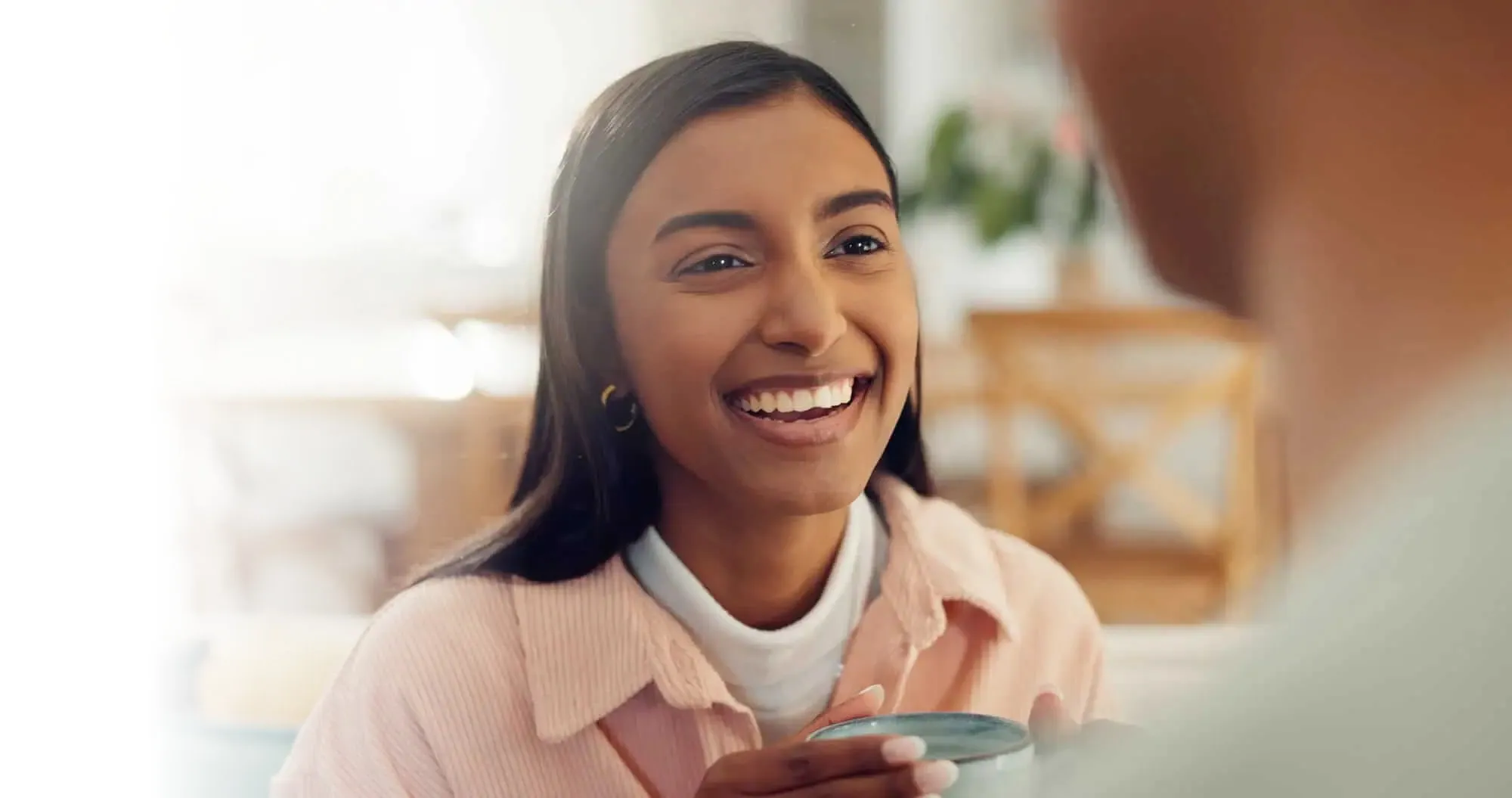 A woman smiles as she holds a spoon in her hand.