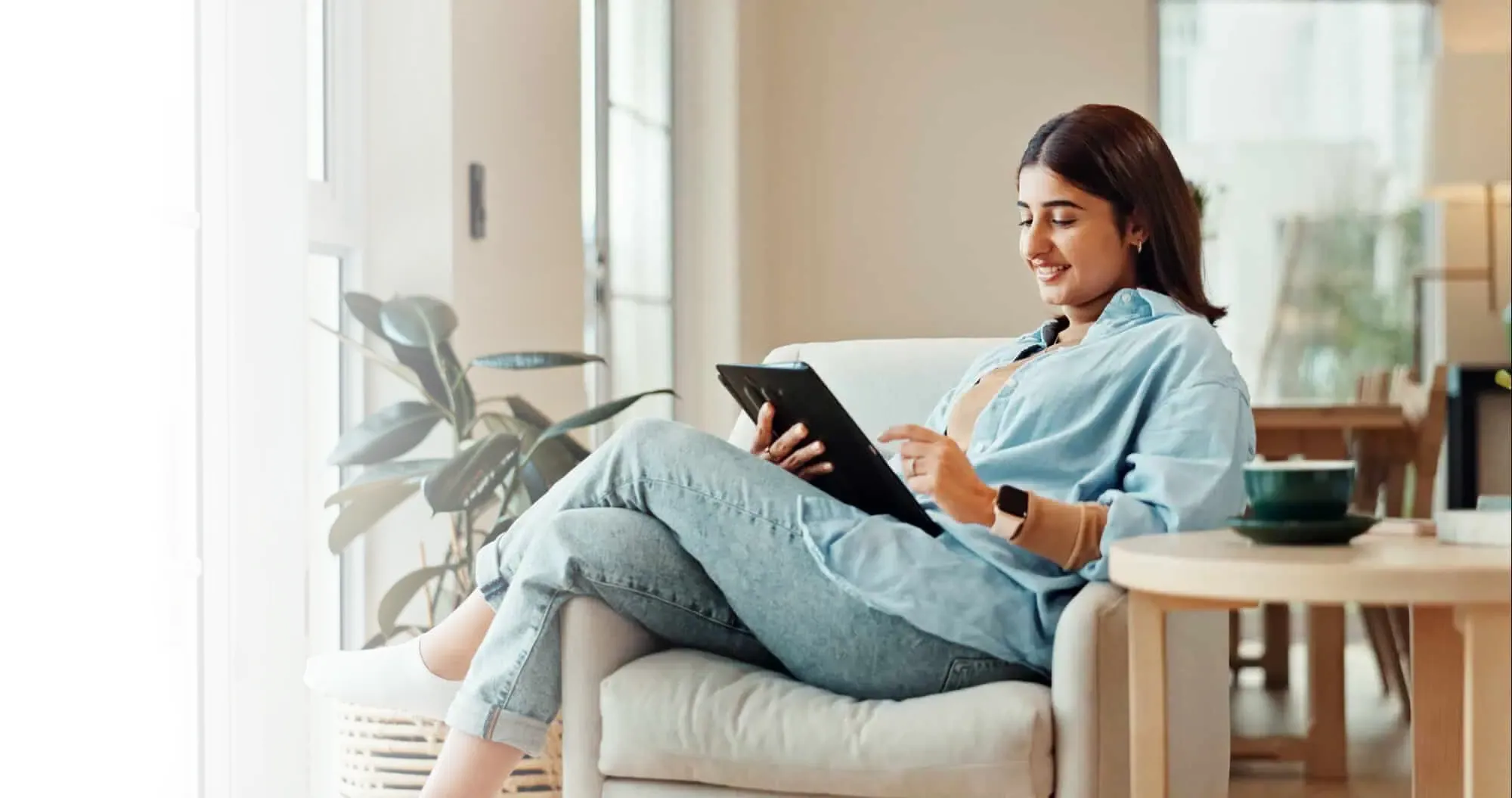 A woman sitting on a couch using a tablet.