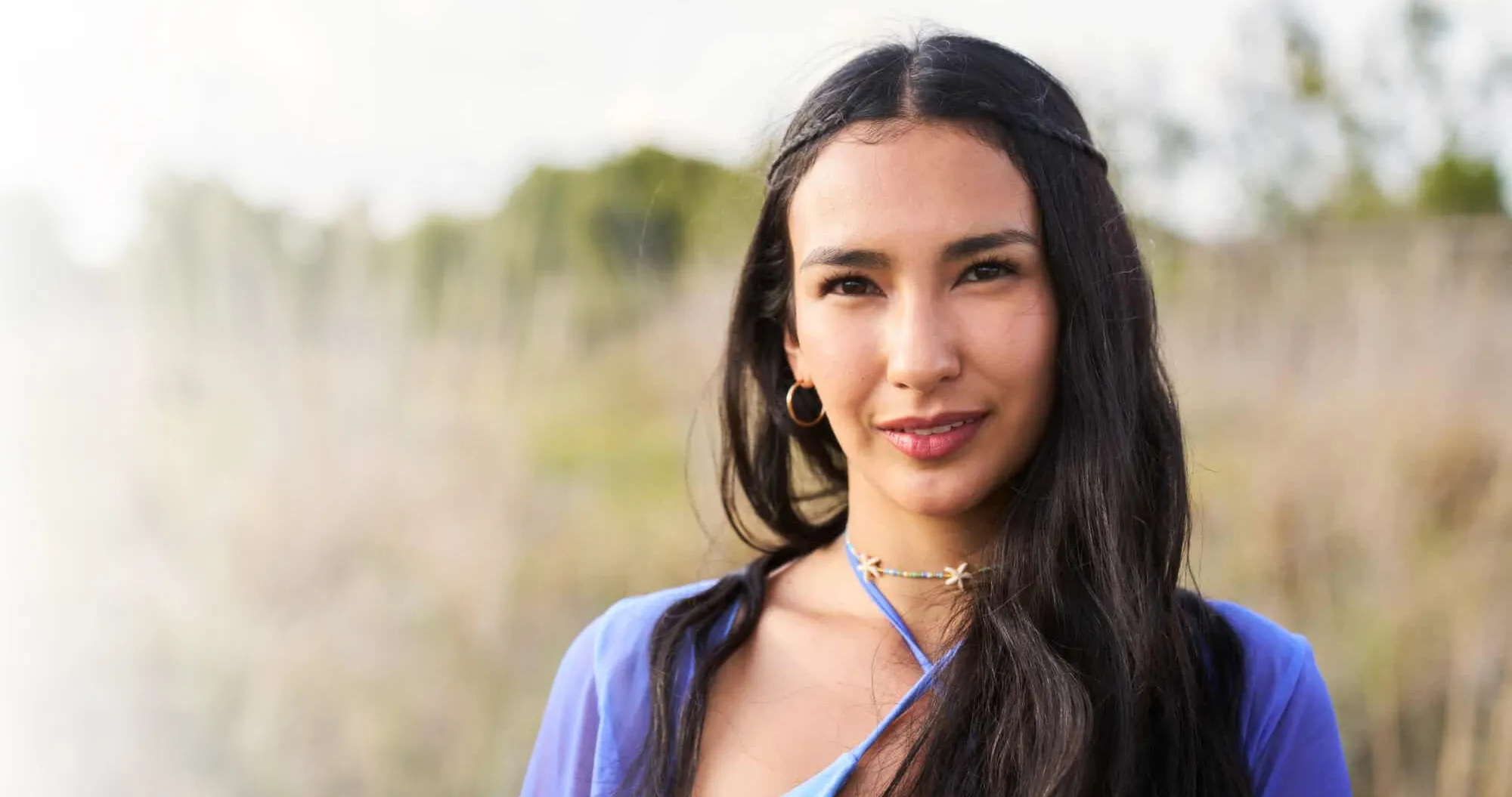 A woman with long dark hair wearing a blue shirt.