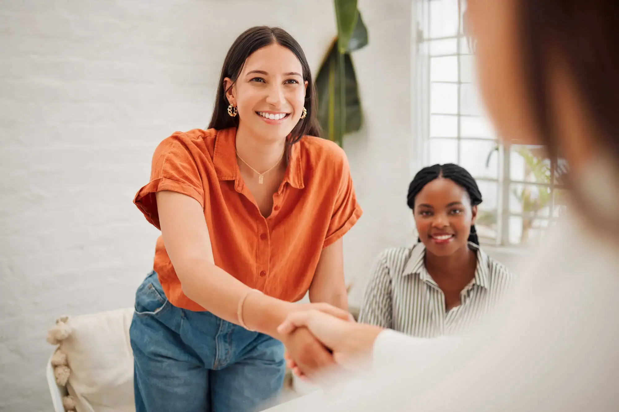 A woman shaking hands with another woman in a room.