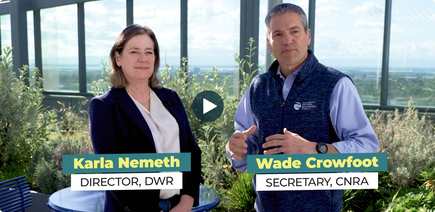 Karla Nemeth, Director of DWR, and Wade Crowfoot, Secretary of CNRA, standing outdoors with plants and a building in the background.