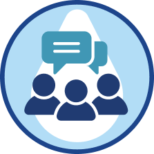 Three dark blue silhouettes of people with two overlapping teal speech bubbles above them inside a light blue and white circular background with a darker blue outer border, symbolizing group communication or discussion.