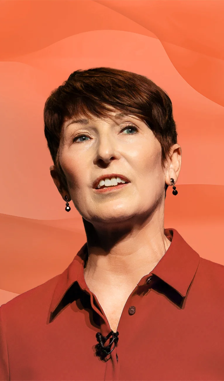 Portrait of a smiling middle-aged woman with short brown hair wearing a red top and earrings.
