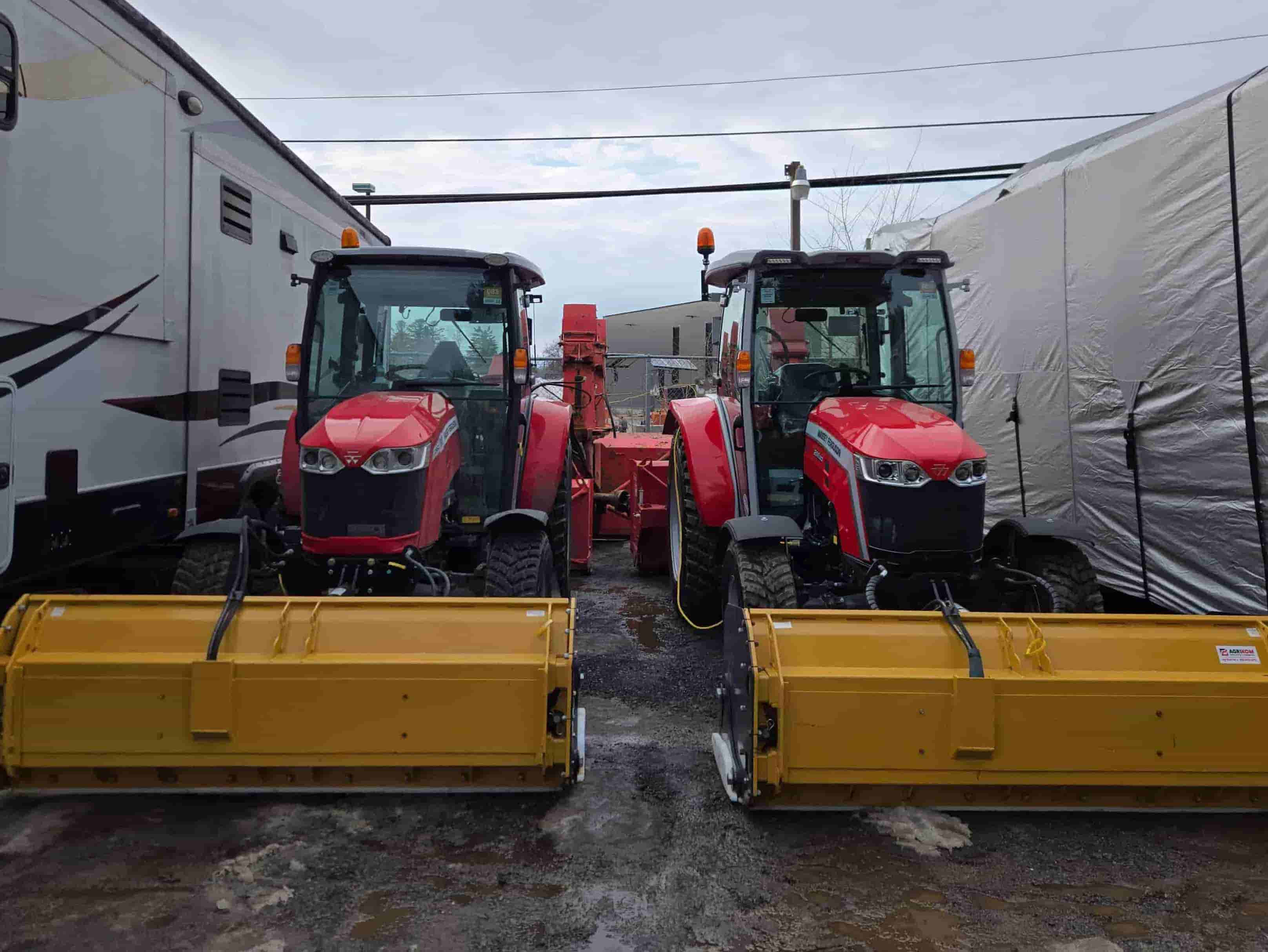 Person operating a red and black snowblower clearing deep snow near a wooden fence.