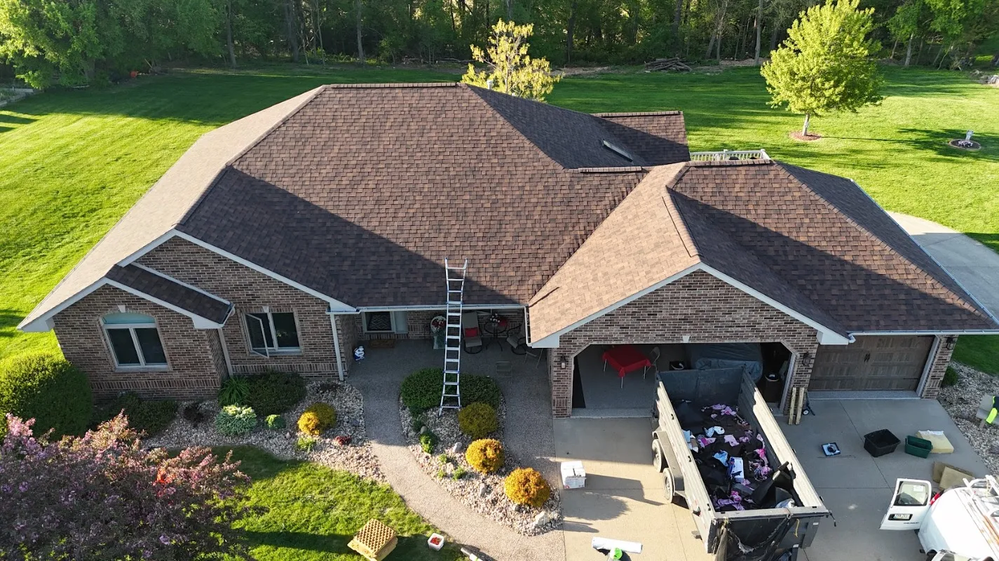 Aerial view of a completed asphalt shingle roof replacement by Passion Exteriors on a brick home in Eastern Iowa