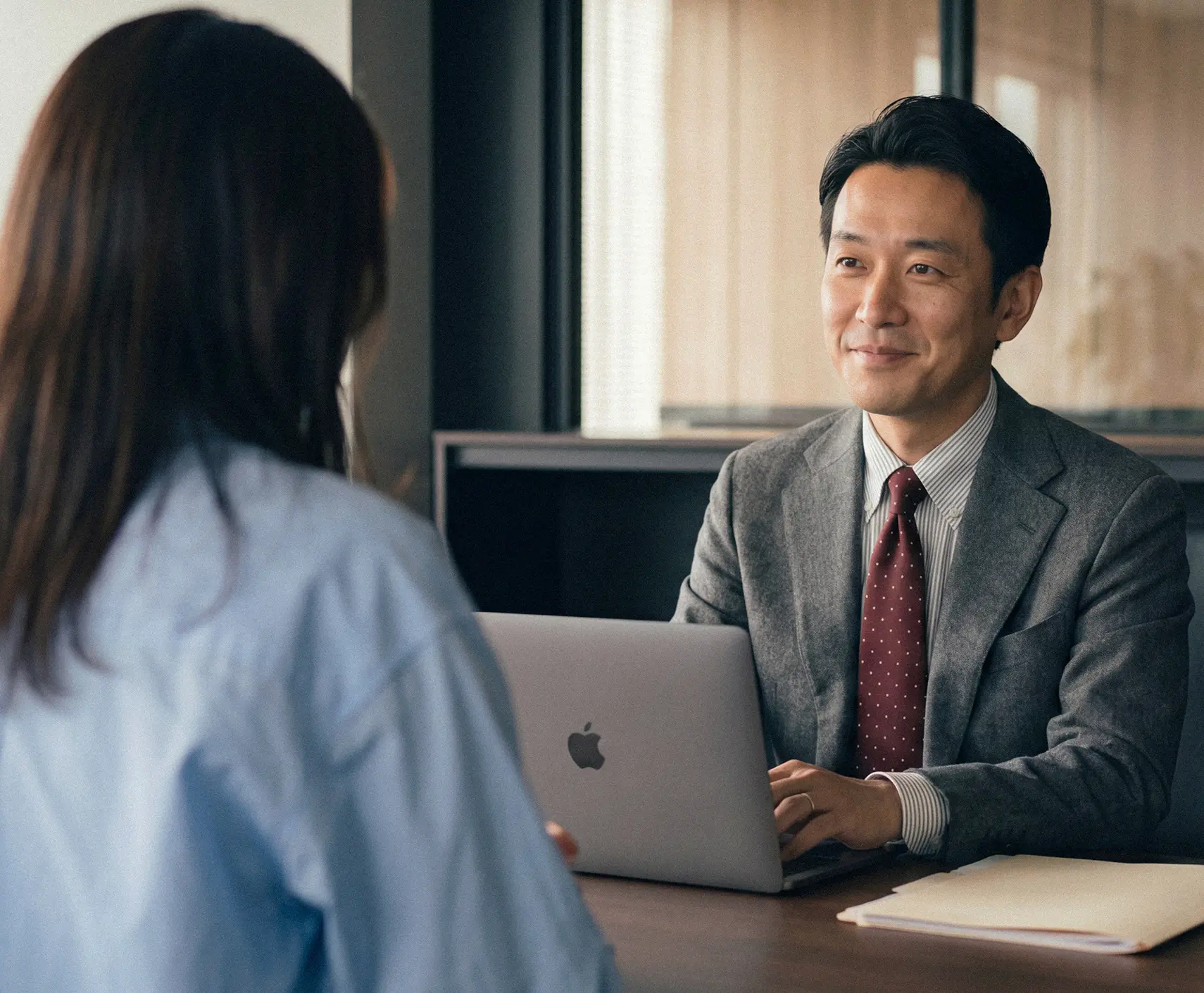 Two business professionals engage in a friendly conversation during a meeting in a bright, modern office filled with plants