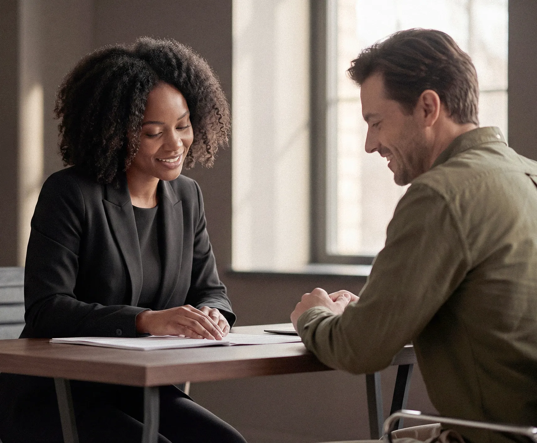 Two business professionals engage in a friendly conversation during a meeting in a bright, modern office filled with plants