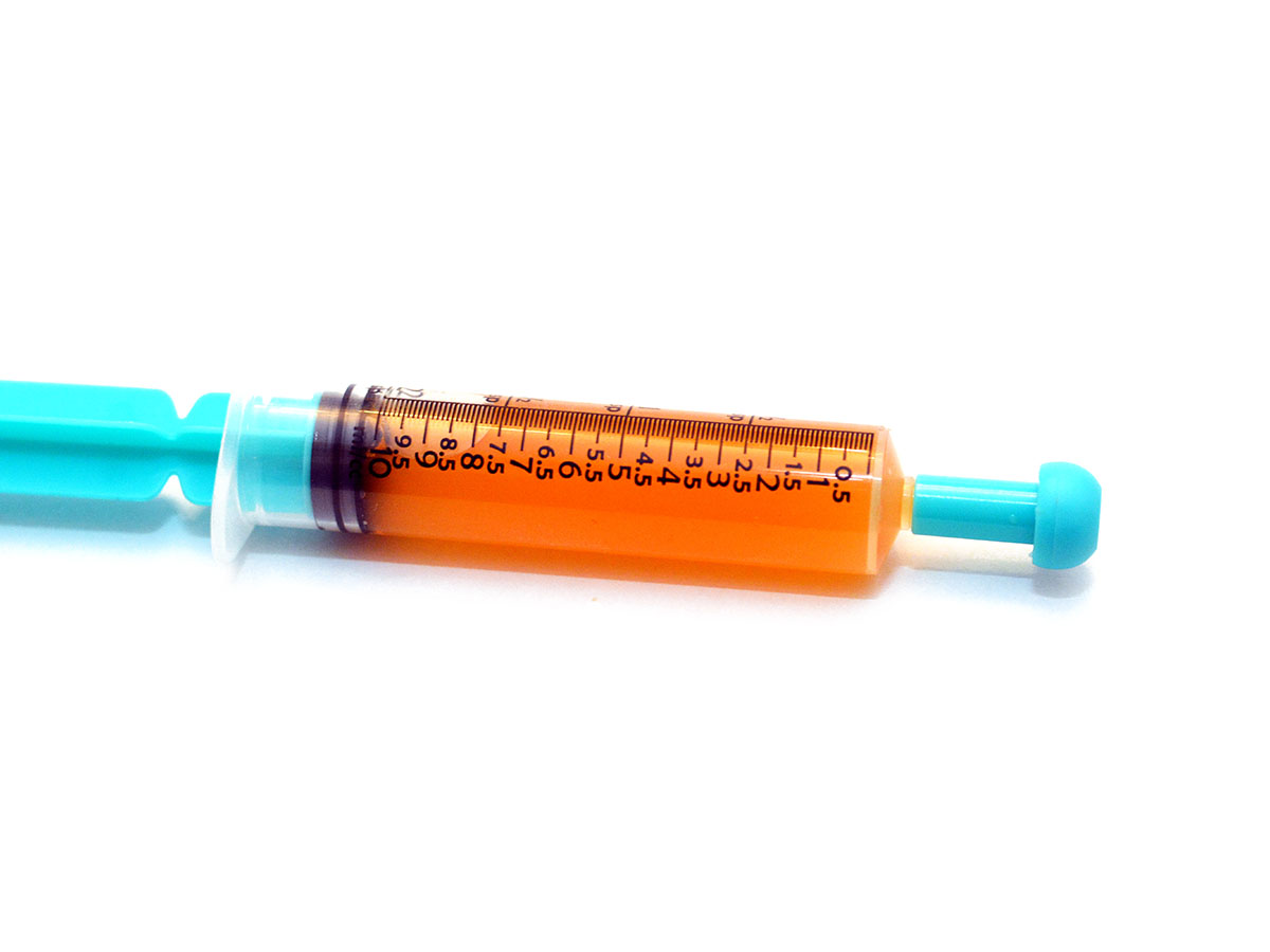 Dablicator with a blue plunger and tip laying on a white background