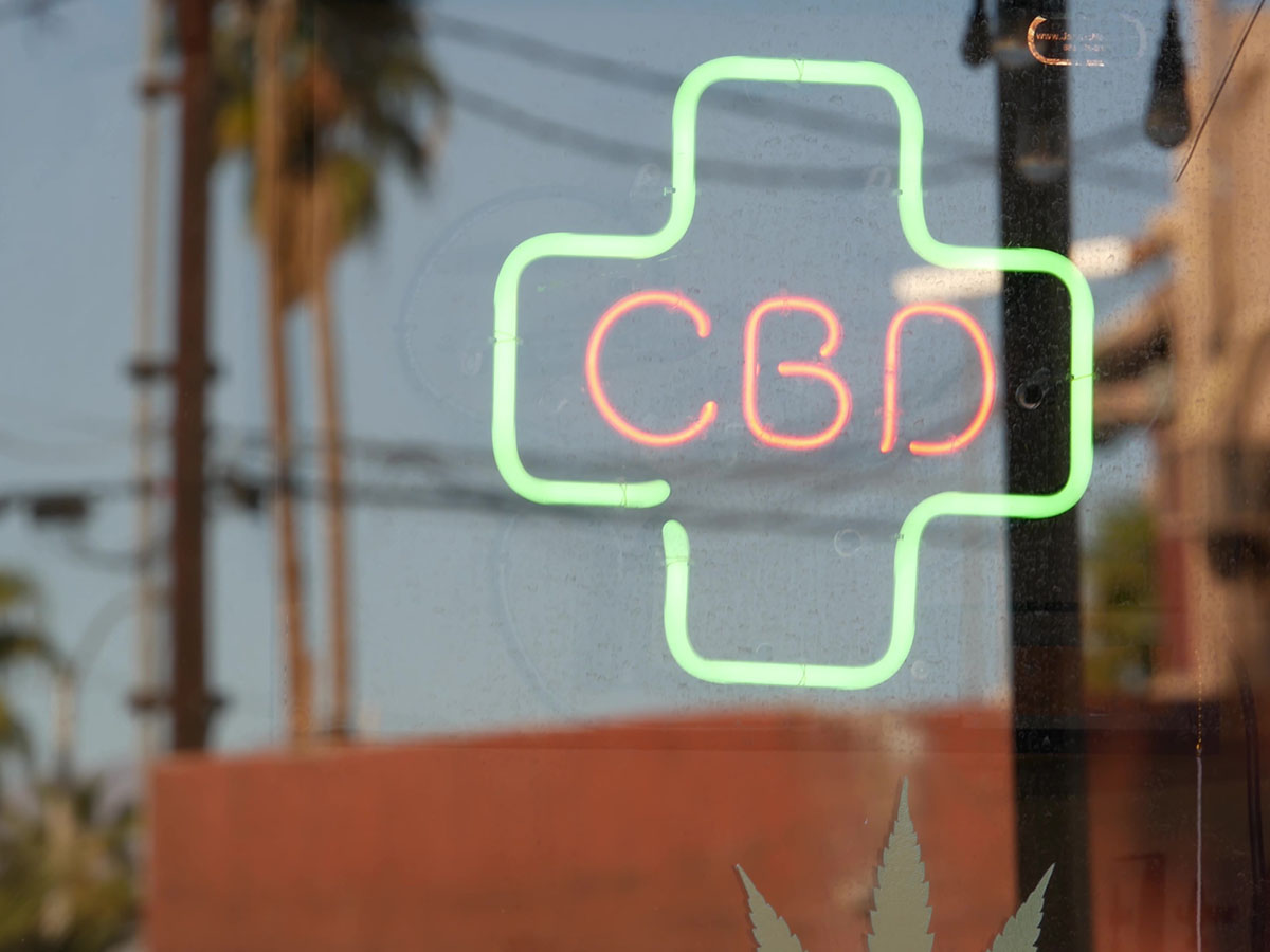 Neon sign of an outline of a medical cross with the letters 'CBD' inside
