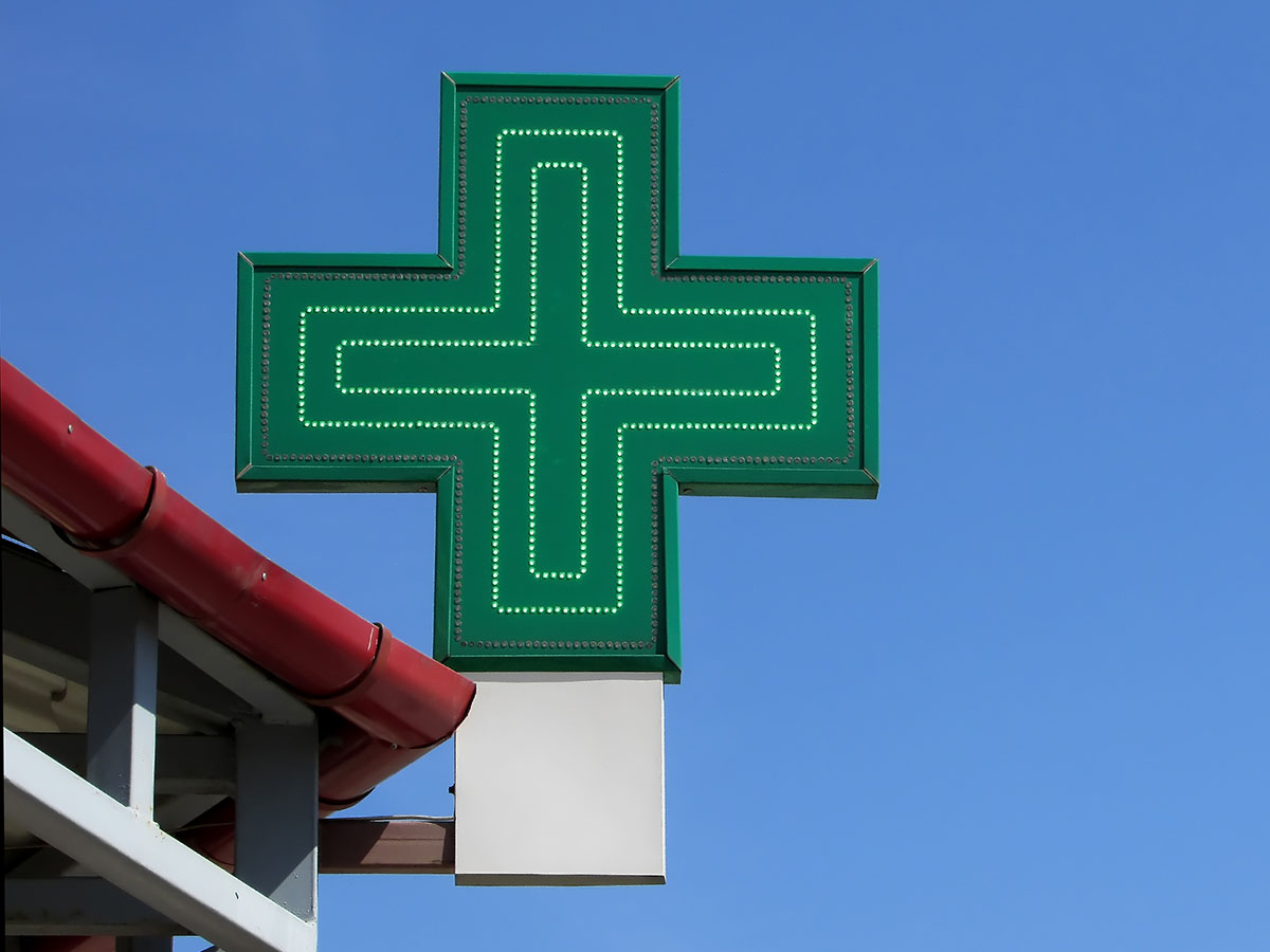 Neon green medical cross sign in front of blue sky