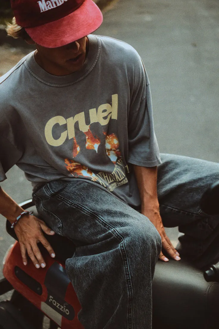 Person wearing a red Marlboro cap and a gray t-shirt with the word 'Cruel' and a fiery graphic, sitting on a scooter labeled 'Fazzio.'