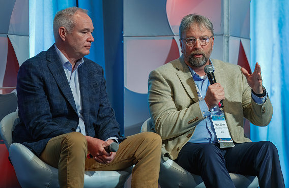 Sack spilling wood pellets next to compressed wood briquettes on a rustic wooden surface with scattered autumn leaves.