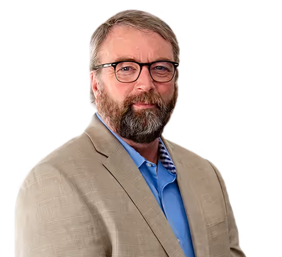 Middle-aged man with beard and glasses wearing a beige blazer and blue shirt.