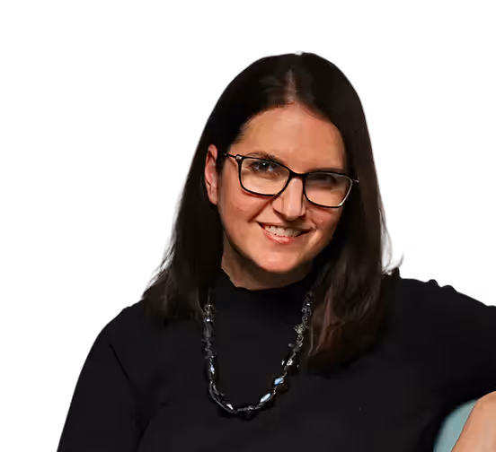Smiling woman with straight dark hair, wearing glasses, a black top, and a beaded necklace.