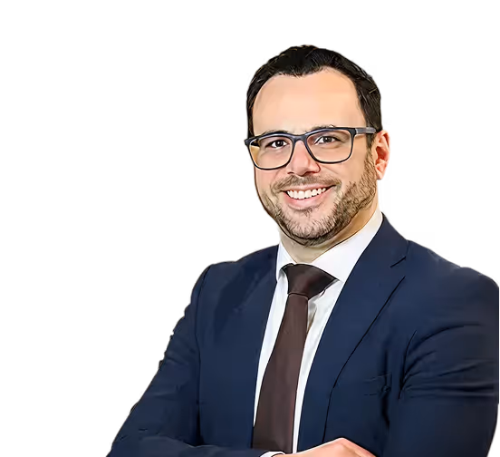 Smiling man with glasses wearing a navy suit, white shirt, and dark tie with arms crossed.