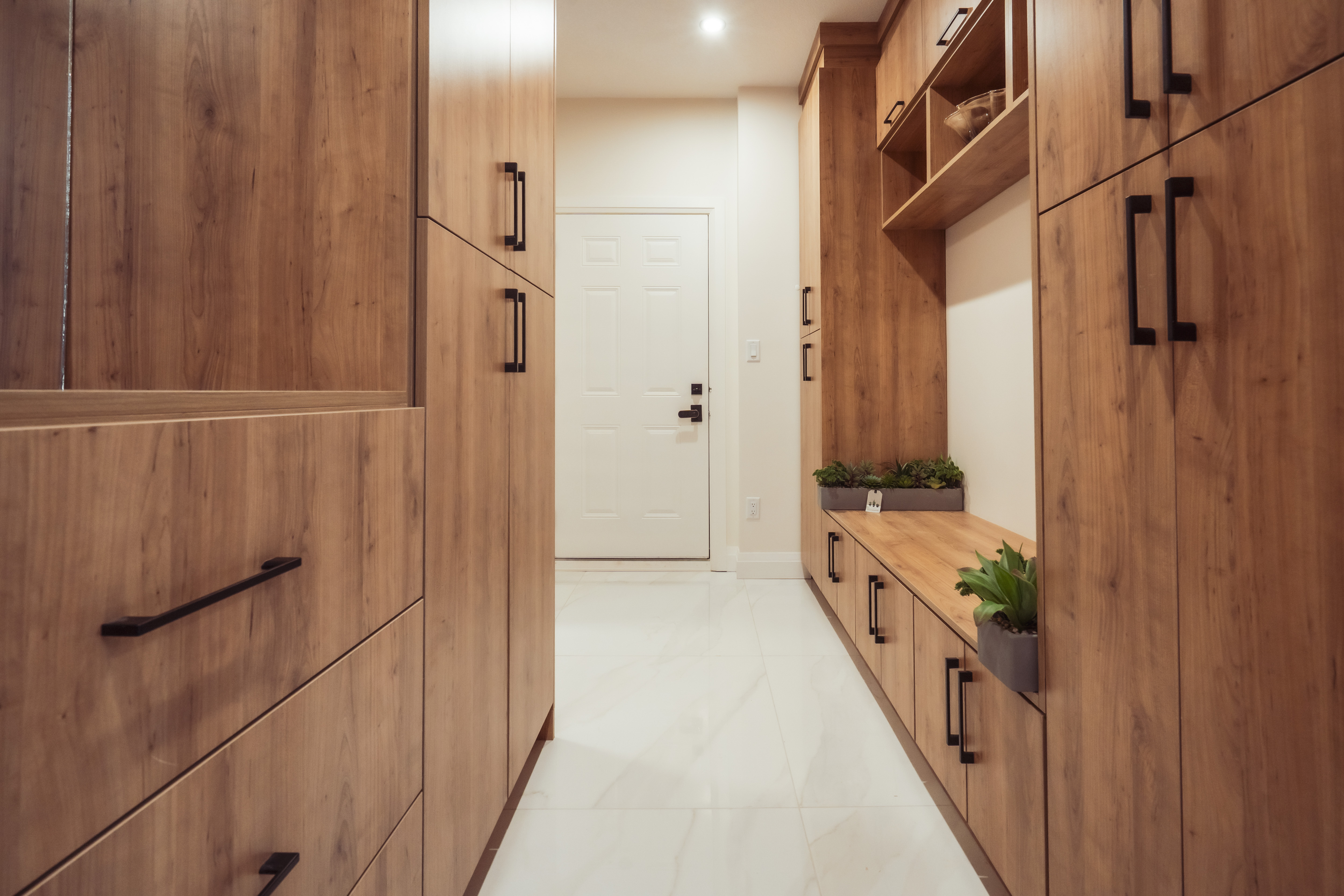 सफा सेतो टाइल्सले ढाकिएको फर्श भएको लकड़ीका थुप्रा र कालो ह्यान्डलहरू सहितको भान्छा कोठा।