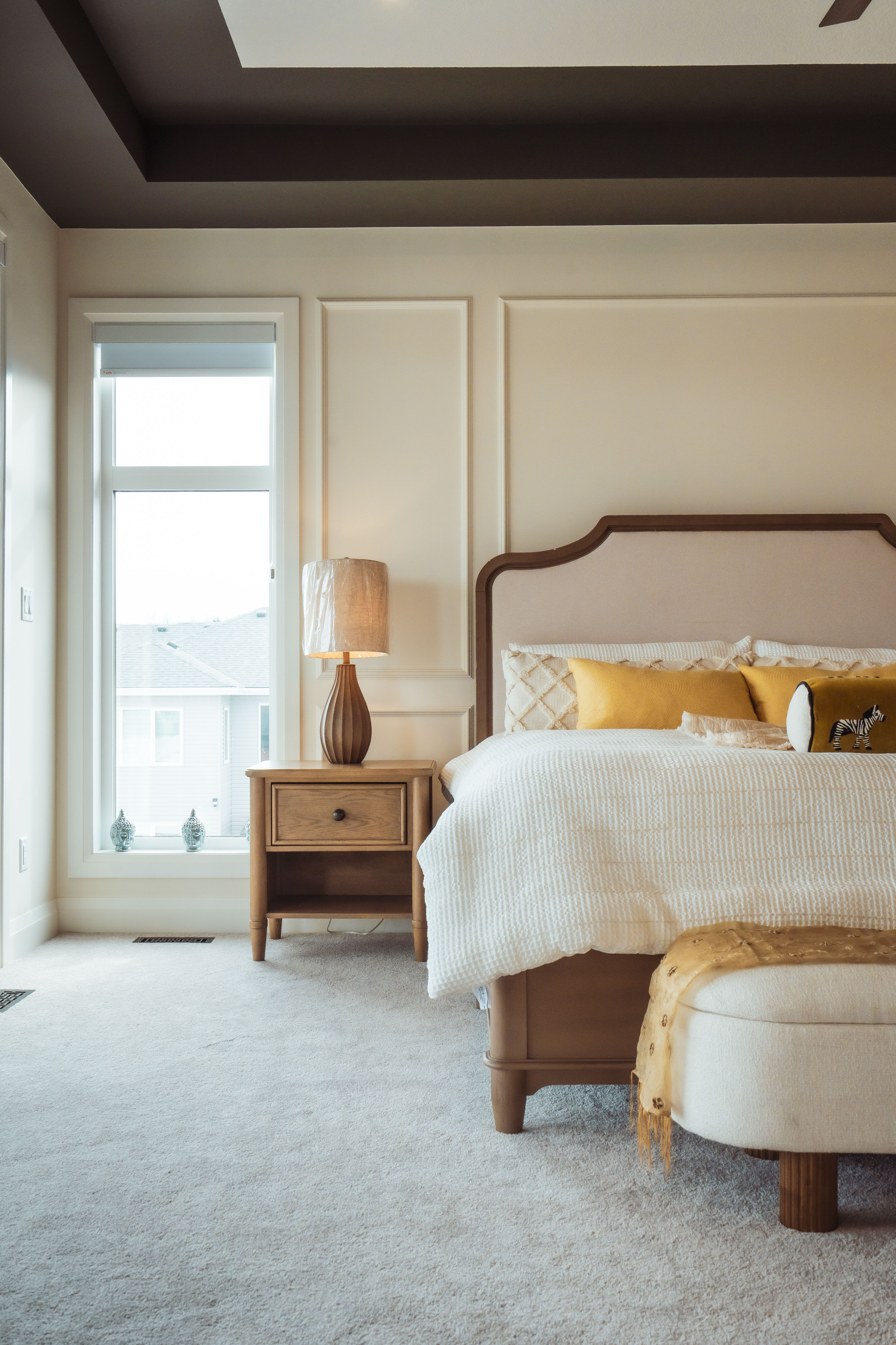 सफा कार्पेट भएको सुन्दर बैजनी शय्या, पहेँलो तकियाहरू र साइड टेबलमा टेबल ल्याम्प सहितको सुशोभित सुनसान शयनकक्ष।