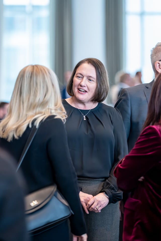 पुरुष र महिलाहरू अन्तरक्रिया गरिरहेका छन्, तिनीहरू आधिकारिक वा नेटवर्किङ कार्यक्रममा छन्।