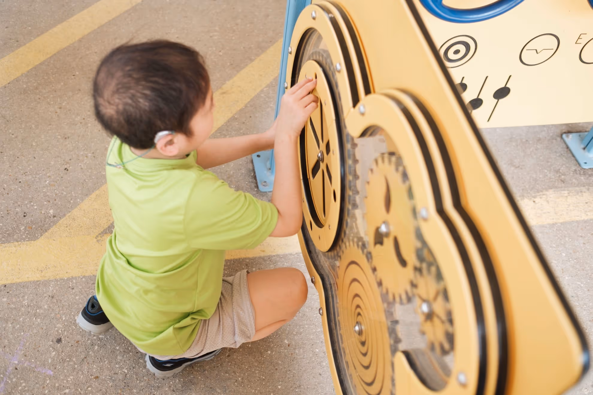 A young boy playing with a mechanical gear toy outside