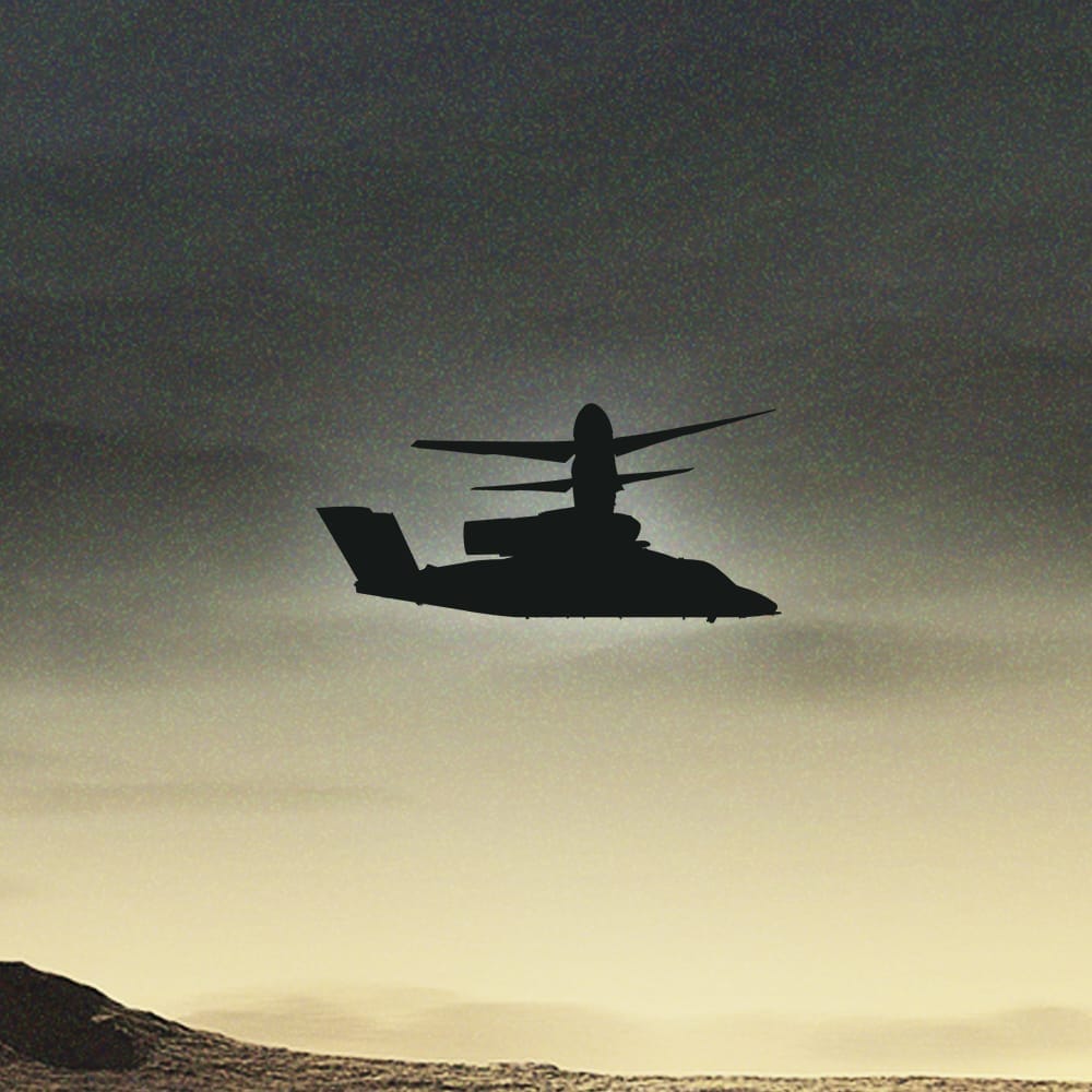 Military helicopter silhouetted against a sunset sky, hovering over a serene landscape.