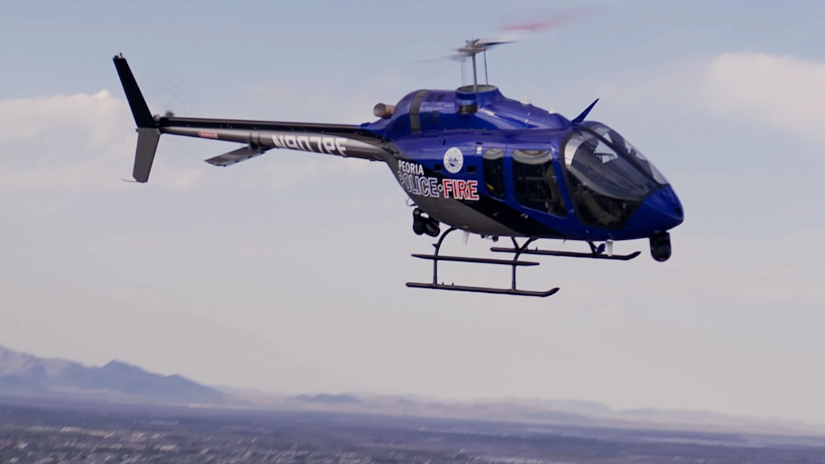 A blue helicopter with "POLICE-FIRE" written on the side flies over a city landscape.