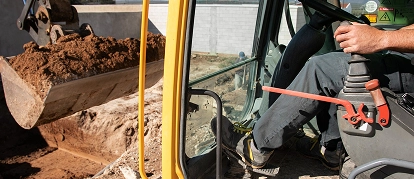 Excavator breaking ground at an active demolition site