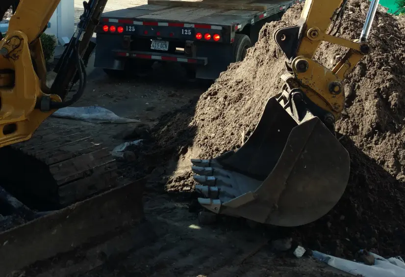 Excavator digging a trench for grease trap installation