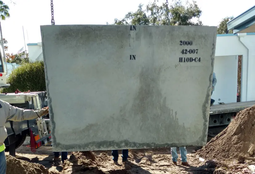 Precast concrete grease trap being positioned for lowering