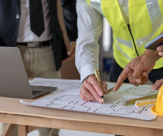Construction Manager looks over blueprints with crew