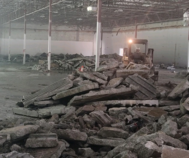 Two workers look out over a construction site with trees
