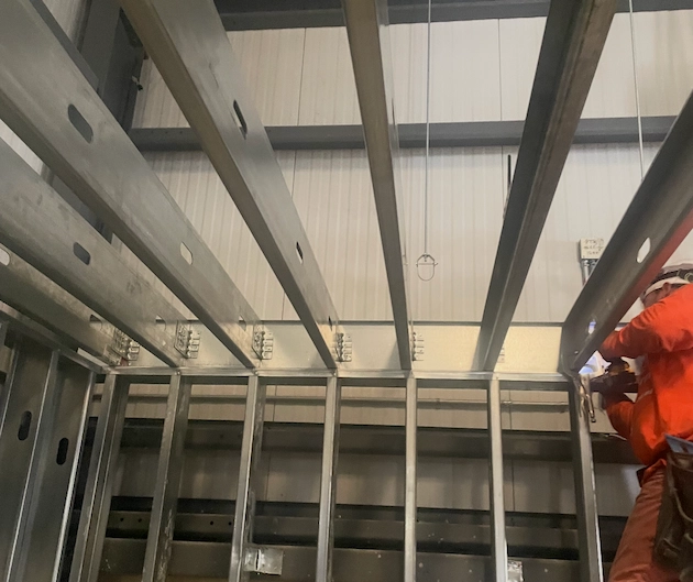 Worker in orange installing metal framing