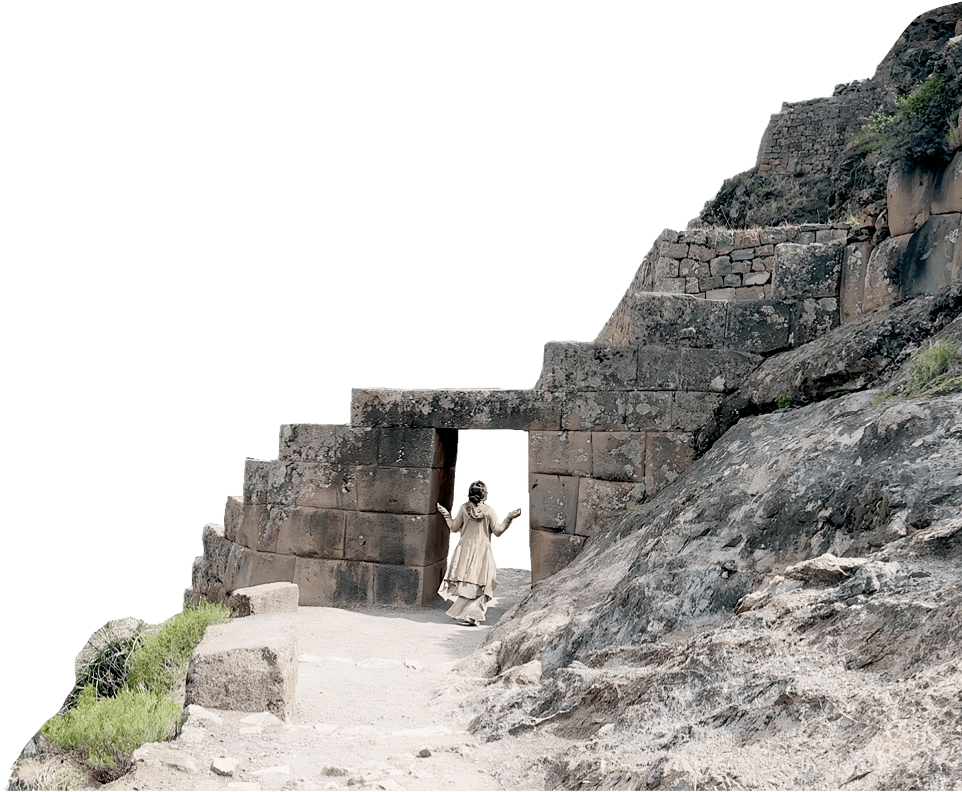 Person in beige outfit walking through an ancient stone doorway carved into rocky terrain.