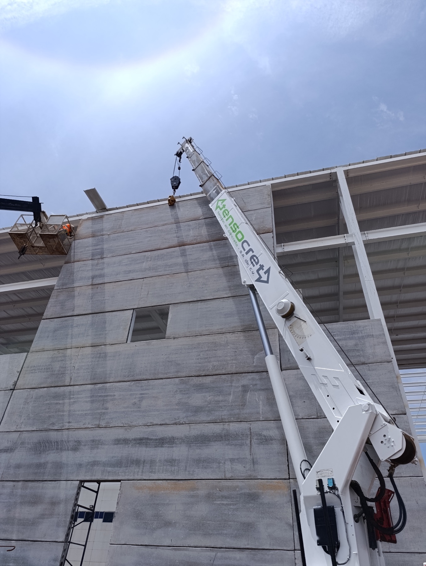 Grúa con logo Tensocret montando muro alveolar