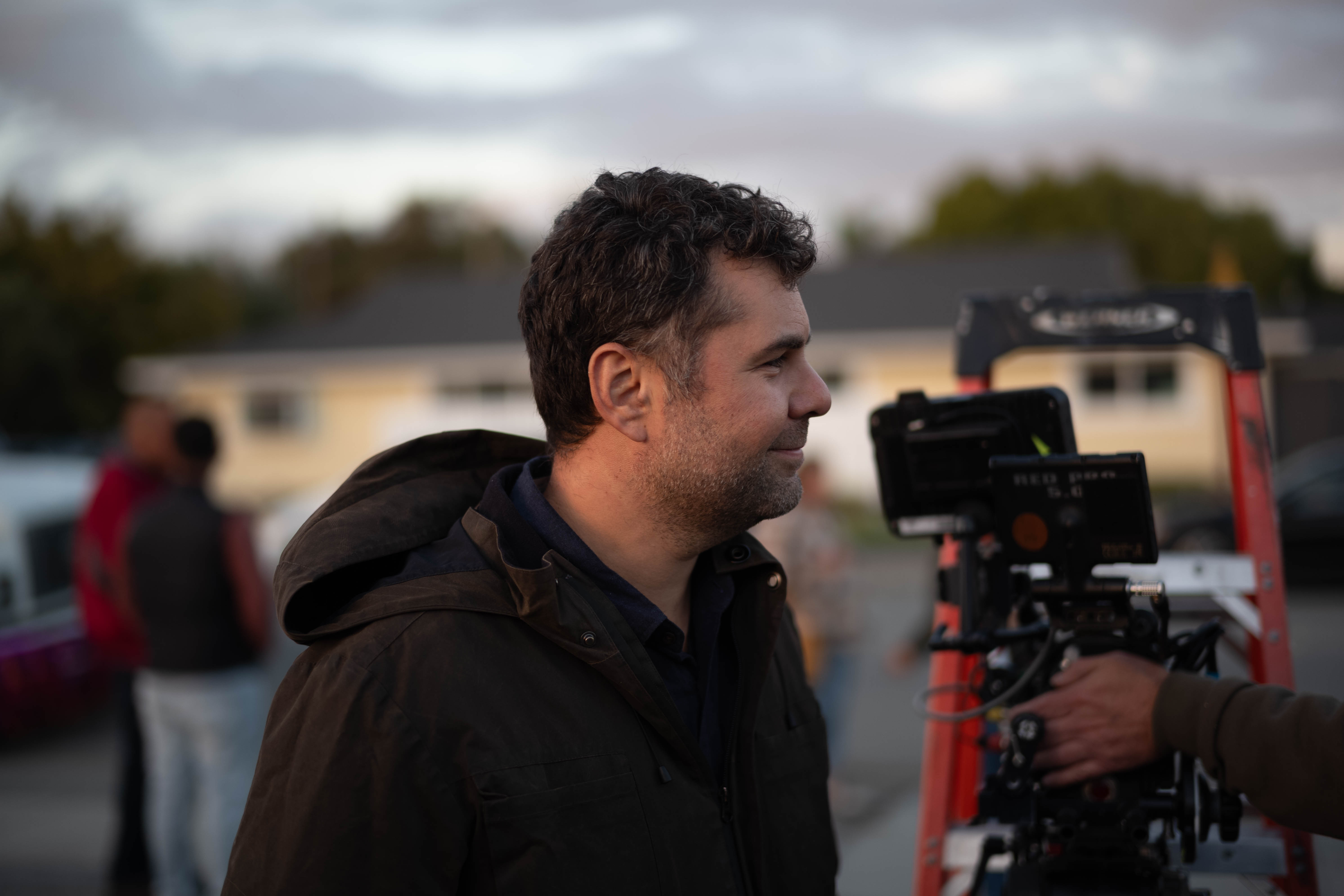 Man standing near a camera setup outdoors