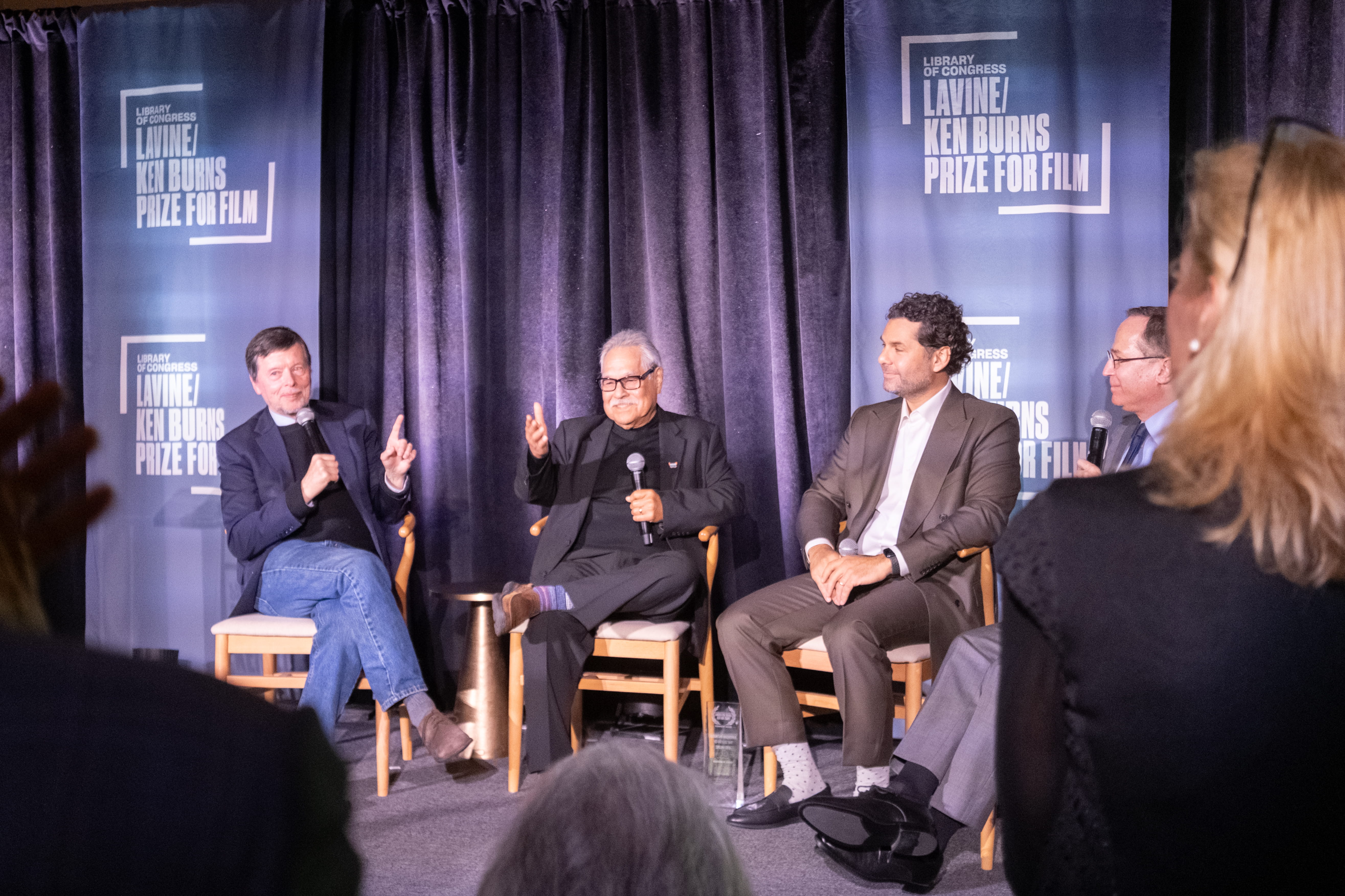 Panel discussion with four speakers holding microphones at a film prize event