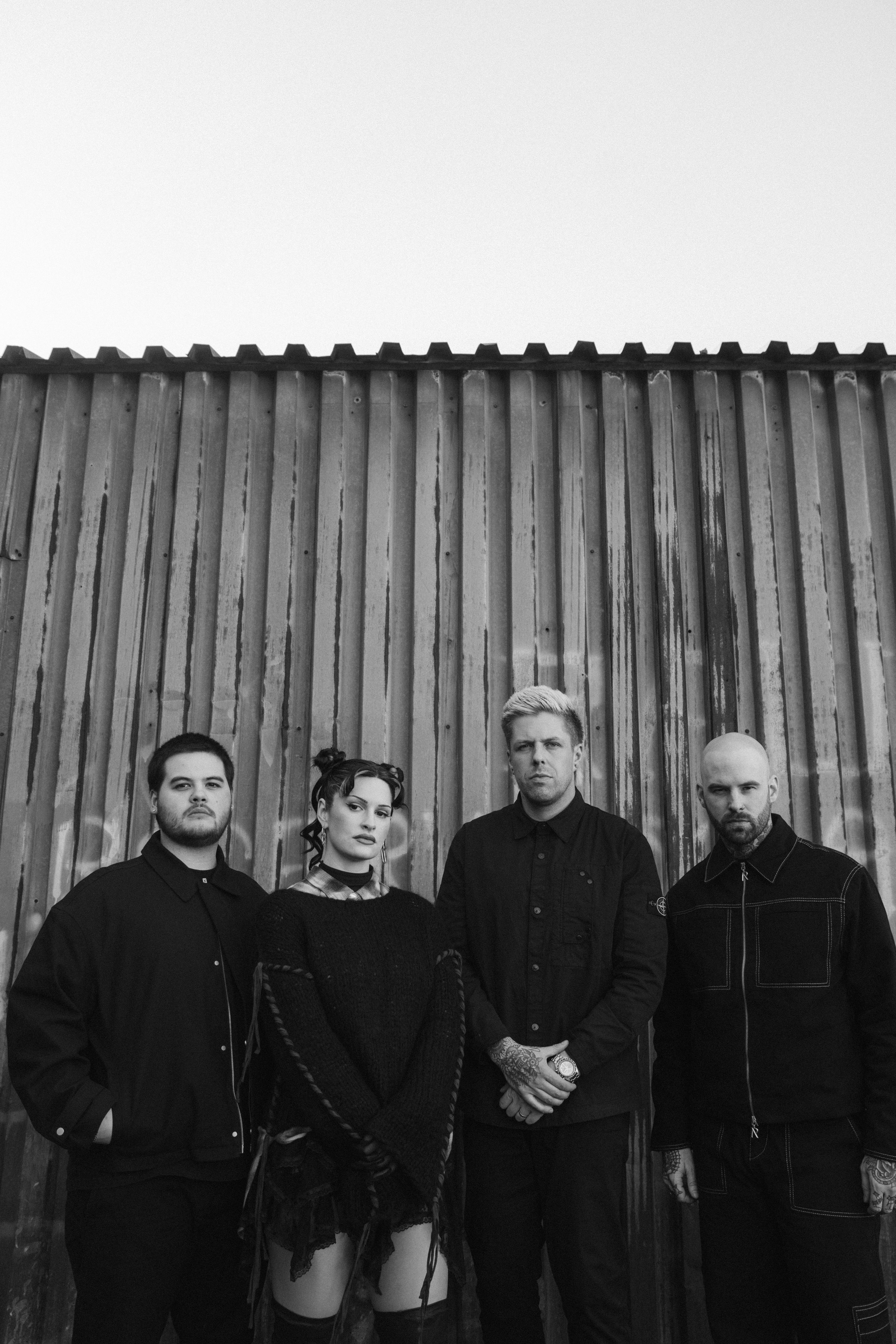 Four people standing in front of a corrugated metal wall