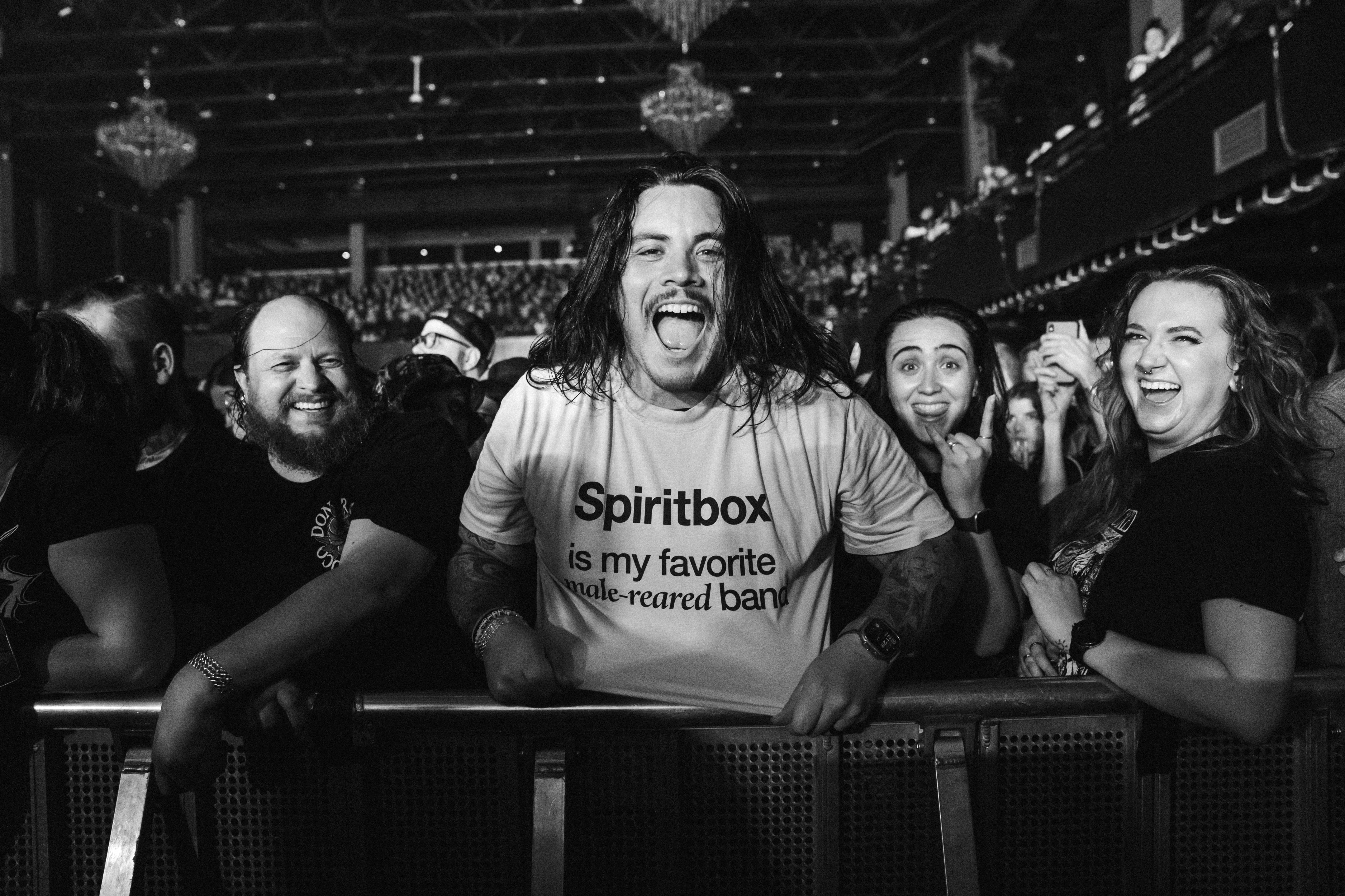 Group of concertgoers smiling and cheering at the front of a crowd