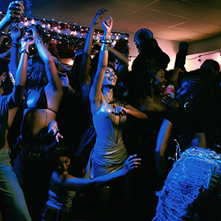 Group of people dancing closely together at a crowded indoor party