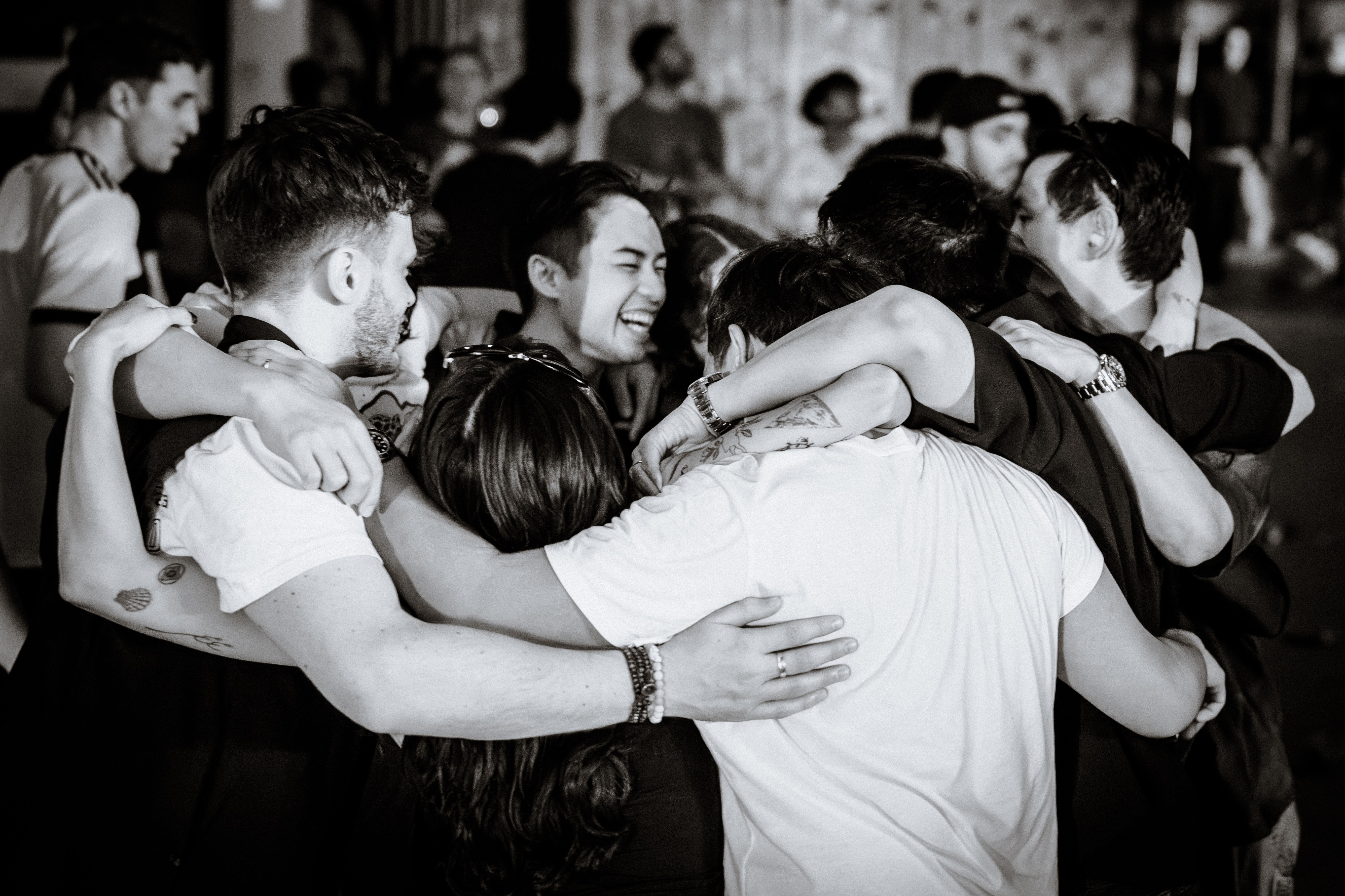 Black-and-white photo of a group hug among concertgoers at a live event