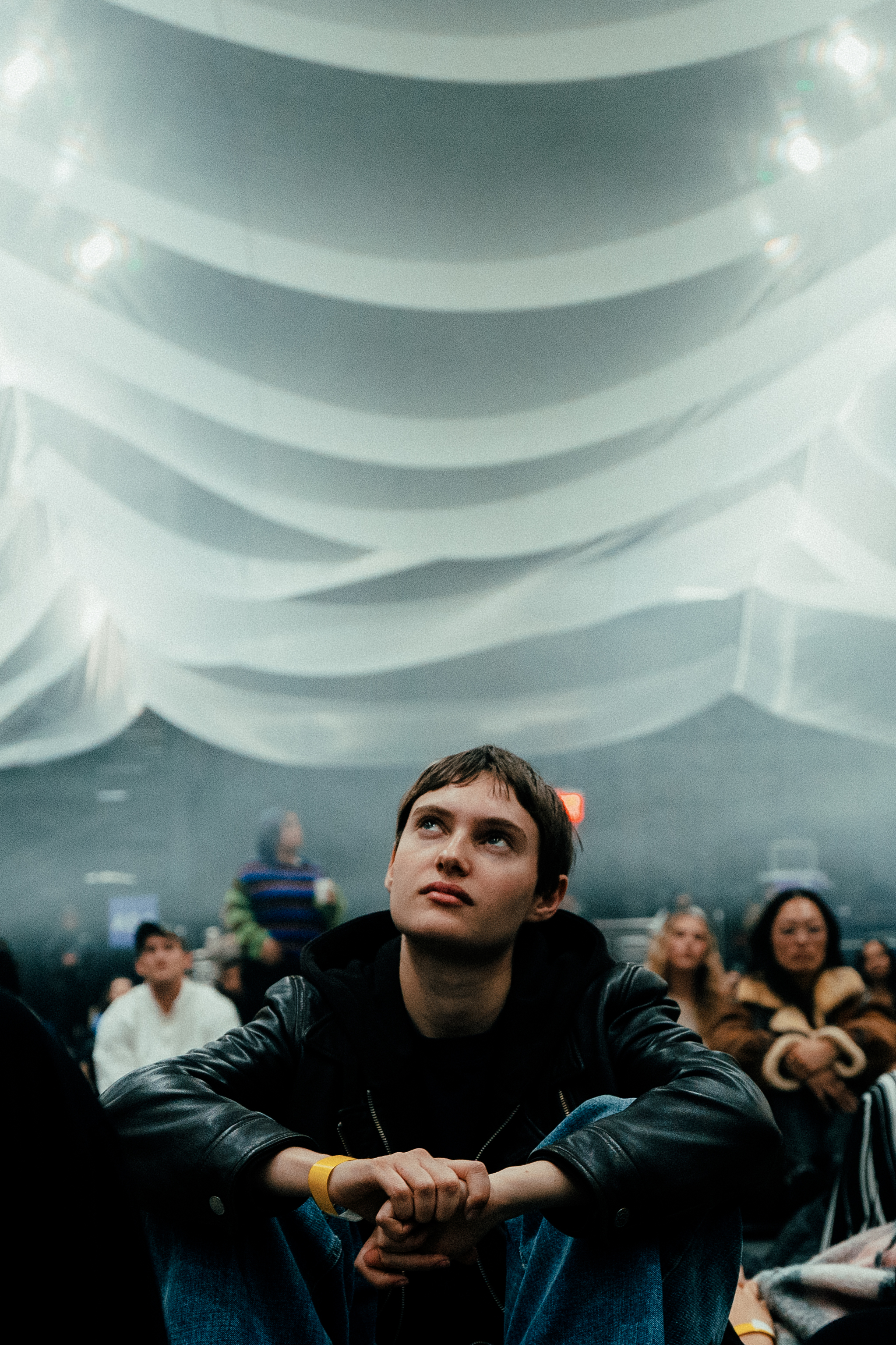 Person seated beneath a glowing fabric installation at an indoor event venue