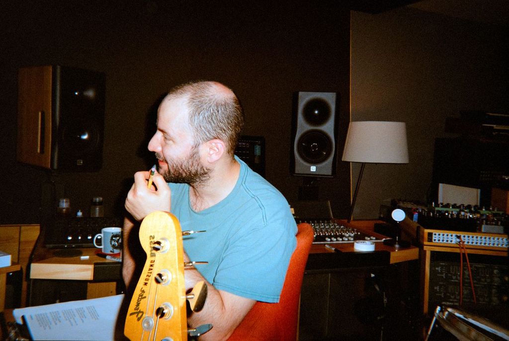 Music producer sitting in a recording studio with a guitar and audio equipment