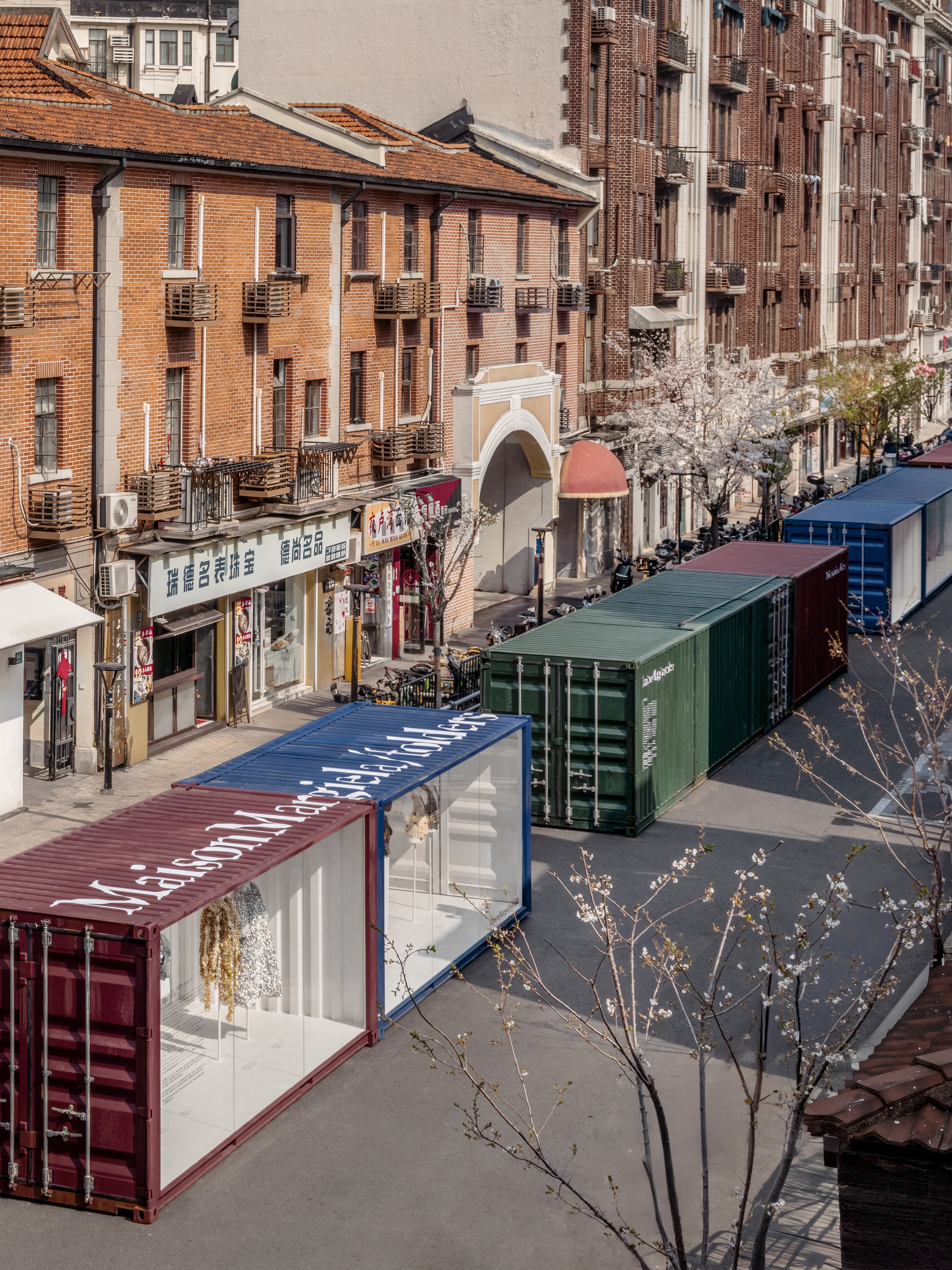 Shipping containers repurposed as storefronts along a city street lined with buildings