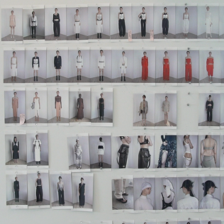 Fashion lineup photos pinned to a wall, showing multiple model looks and outfit details.