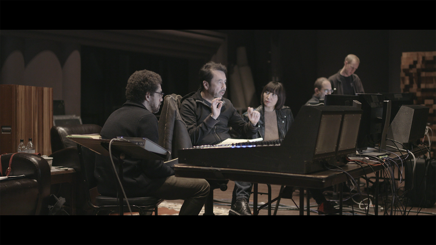 People collaborating at audio mixing console.