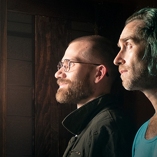 Two people looking out a doorway in dim light.